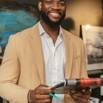 Smiling black businessman holding documents in a modern office setting.